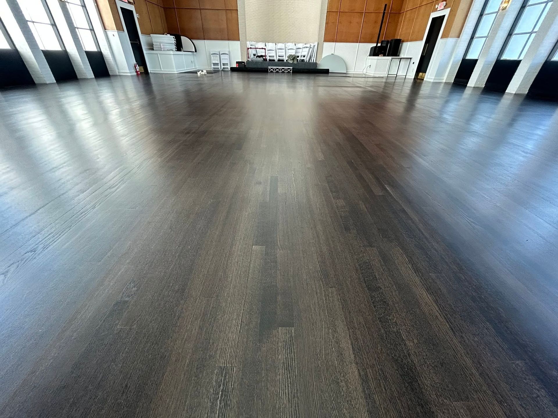 Empty modern hall with dark wood floor and tables at the far end