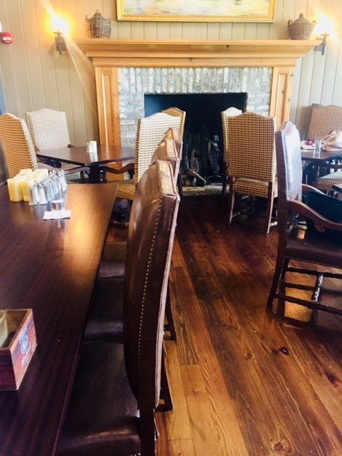 Wood-paneled dining room with white chairs, dark table, and a fireplace mantel on the back wall