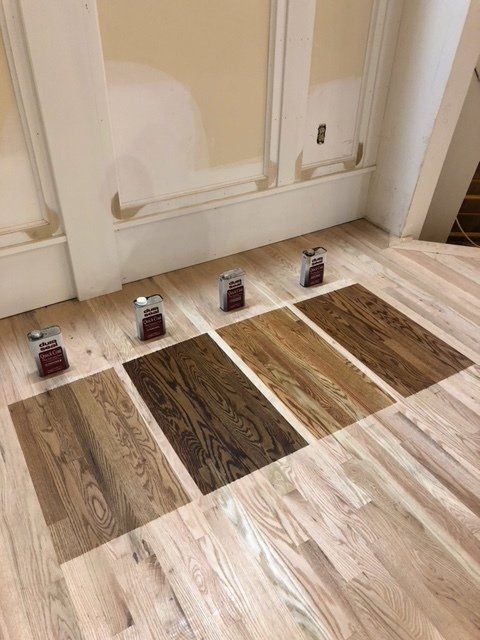 Flooring samples laid out on a light wood floor in front of a doorway