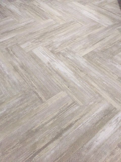 Light wood herringbone floor pattern in soft beige and gray tones