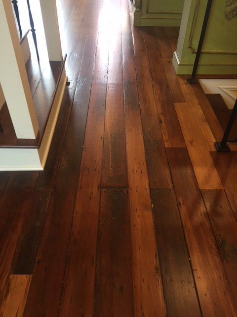Shiny hardwood hallway floor with long planks and green walls on both sides
