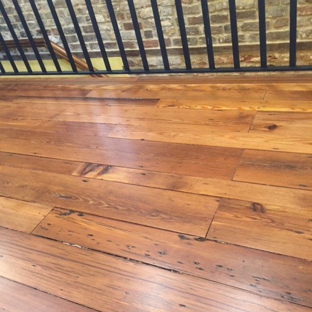 Wooden deck boards with a black metal railing along the edge