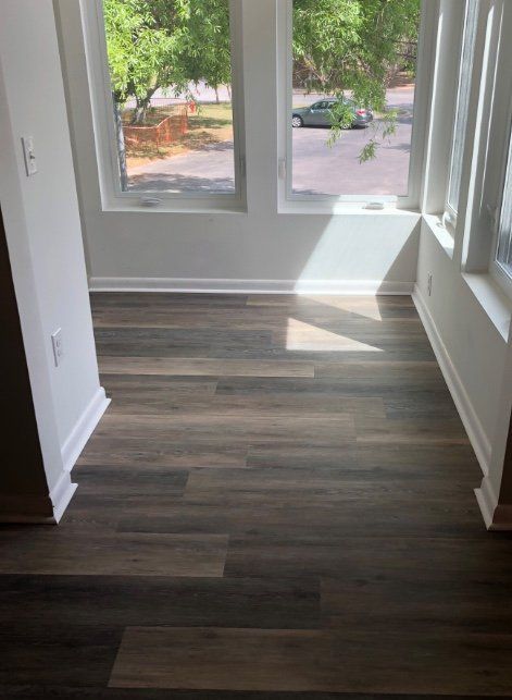 Empty room with wood flooring and large windows overlooking greenery