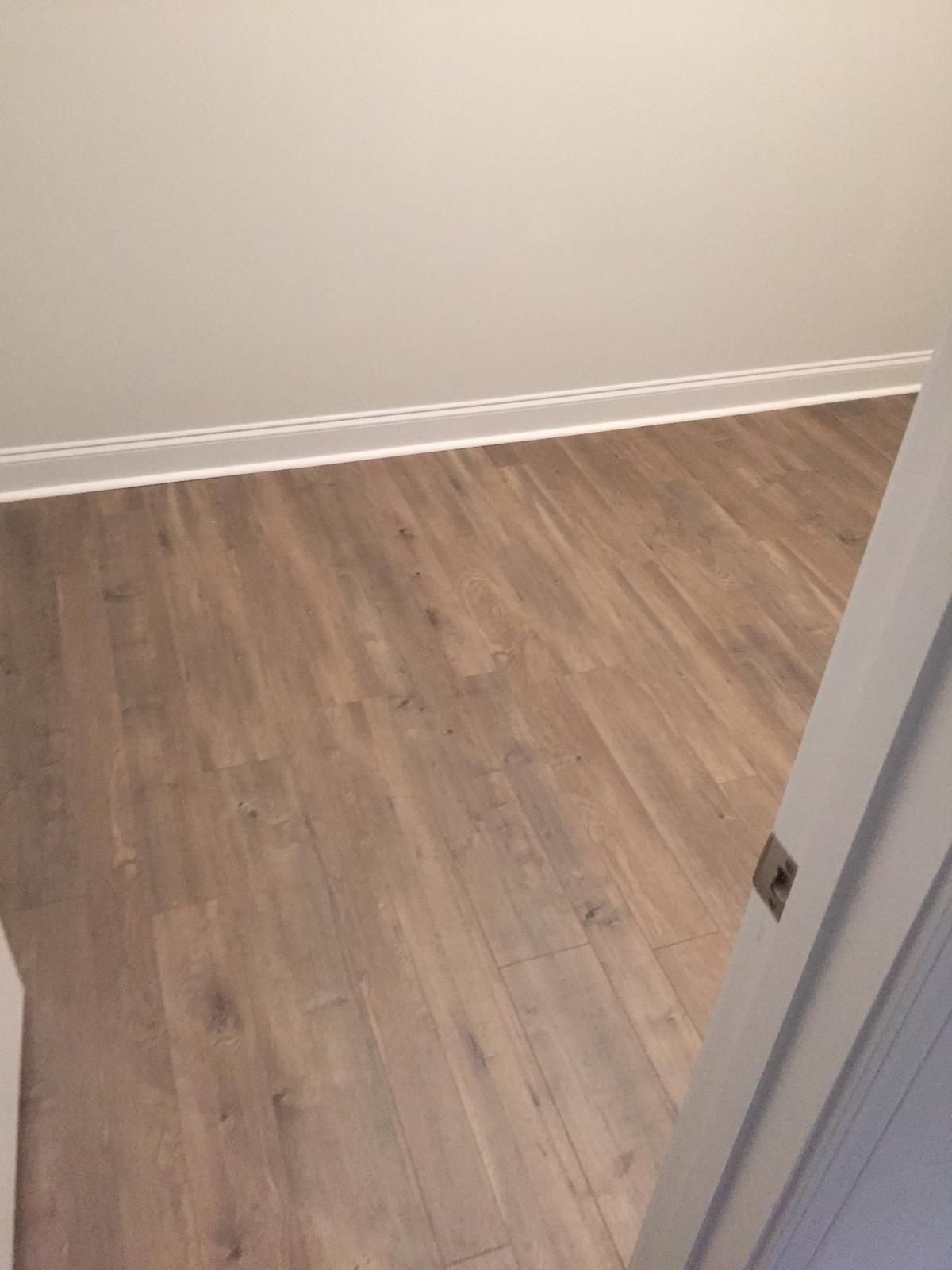 Empty room with light wood flooring, white walls, and an open doorway