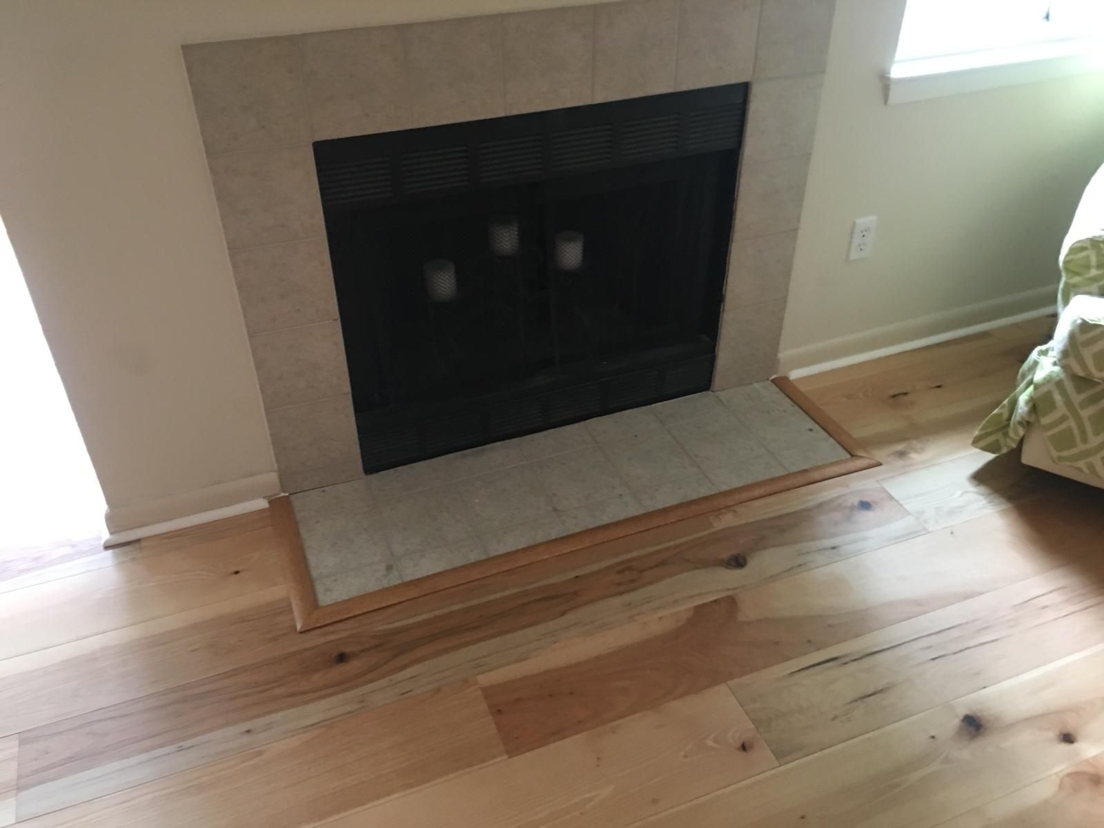 Living room fireplace with beige tile hearth and light wood floor tiles surrounding it