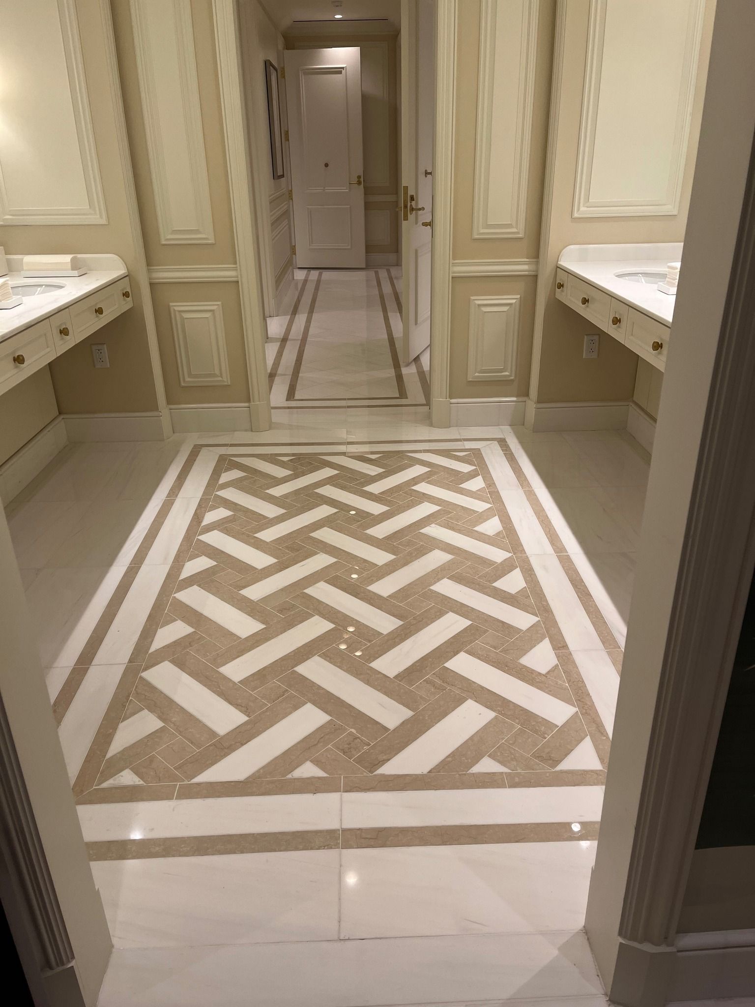 Elegant cream hallway with patterned tile floor and vanity counters on both sides