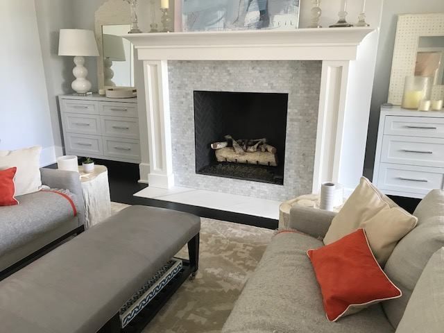 Bright living room with a white fireplace, gray sofas, and coral accent pillows