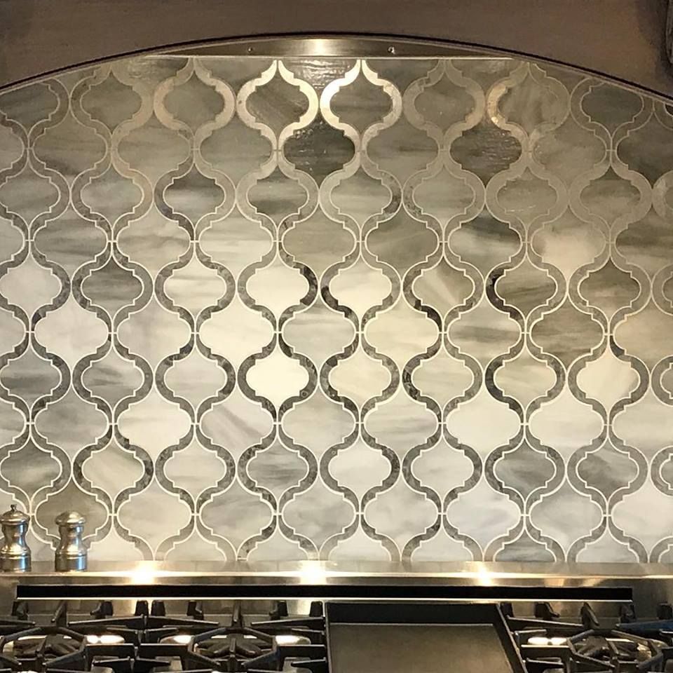 Decorative silver geometric tile backsplash above a stainless steel stove and countertop