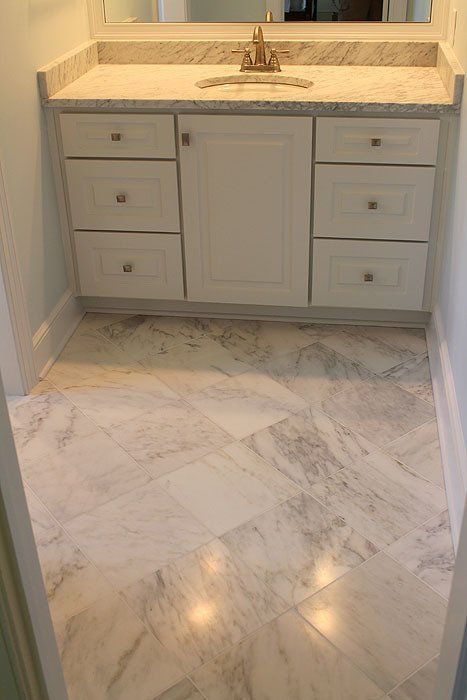Marble-floored bathroom with a white vanity and countertop sink in front of a mirror