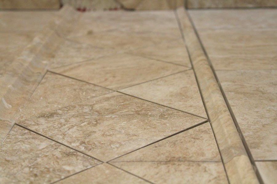 Beige tiled floor with geometric grout lines and a raised border strip