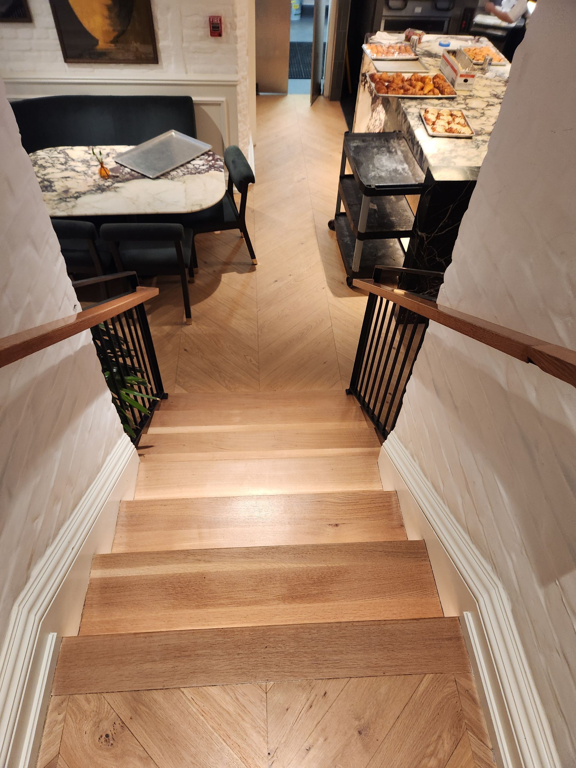 Wooden staircase leading to a living room and dining area with couches and a table.