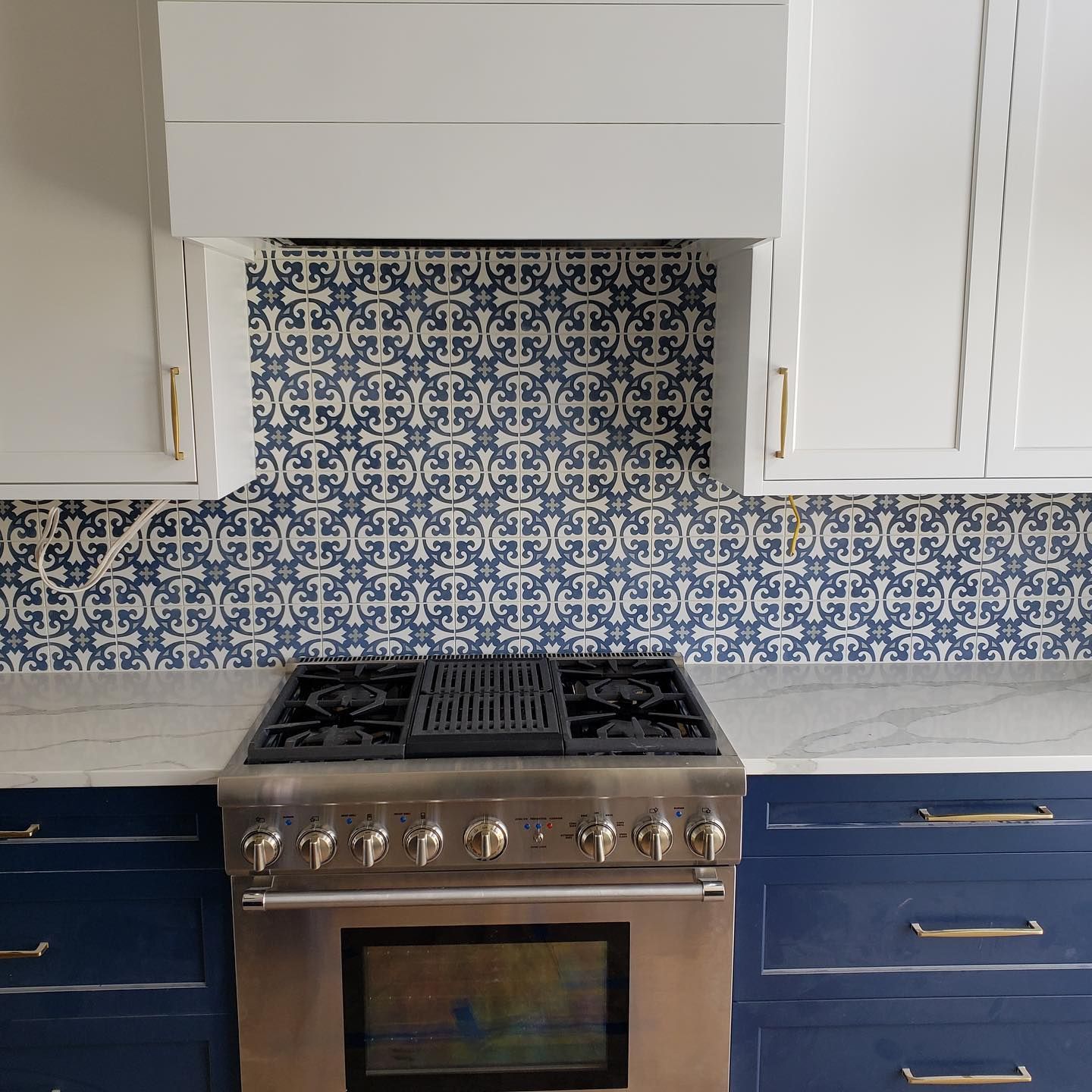 Modern kitchen range with blue-and-white patterned tile backsplash and white cabinets