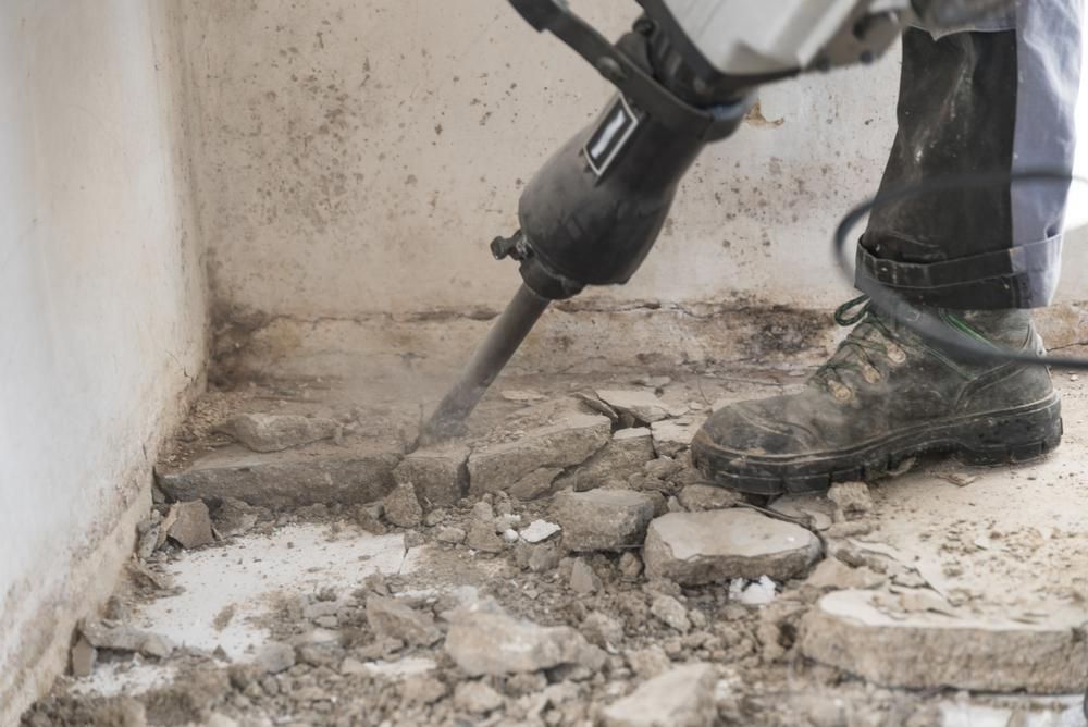 A Person is Using a Hammer to Break Up Concrete — Demco in Currumbin Waters, QLD