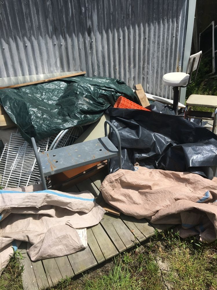 A Pile of Trash is Sitting on a Wooden Deck in Front of a Shed — Demco In Tweed Shire, NSW