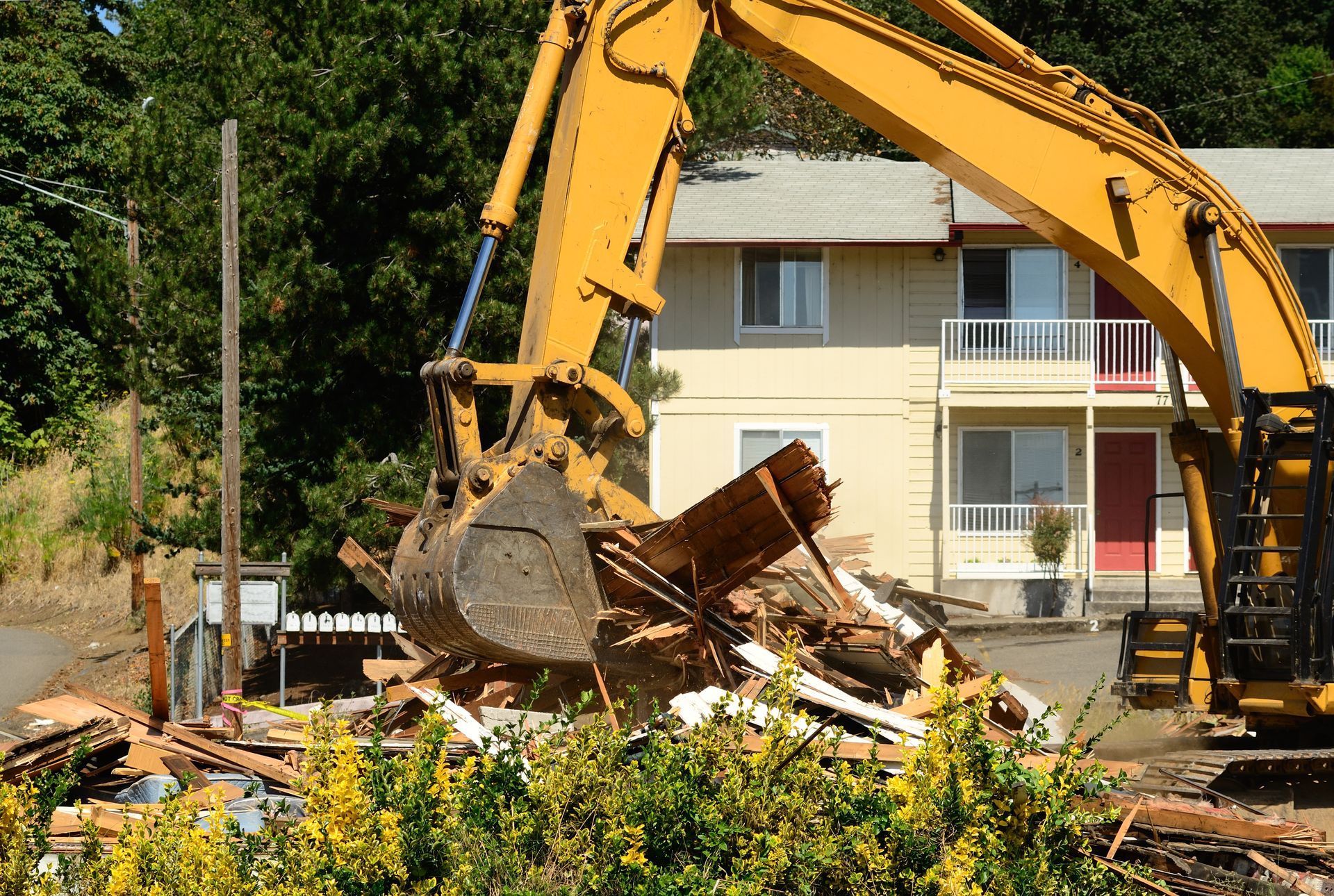 A Large Yellow Excavator is Demolishing a House — Demco In Byron Bay, NSW