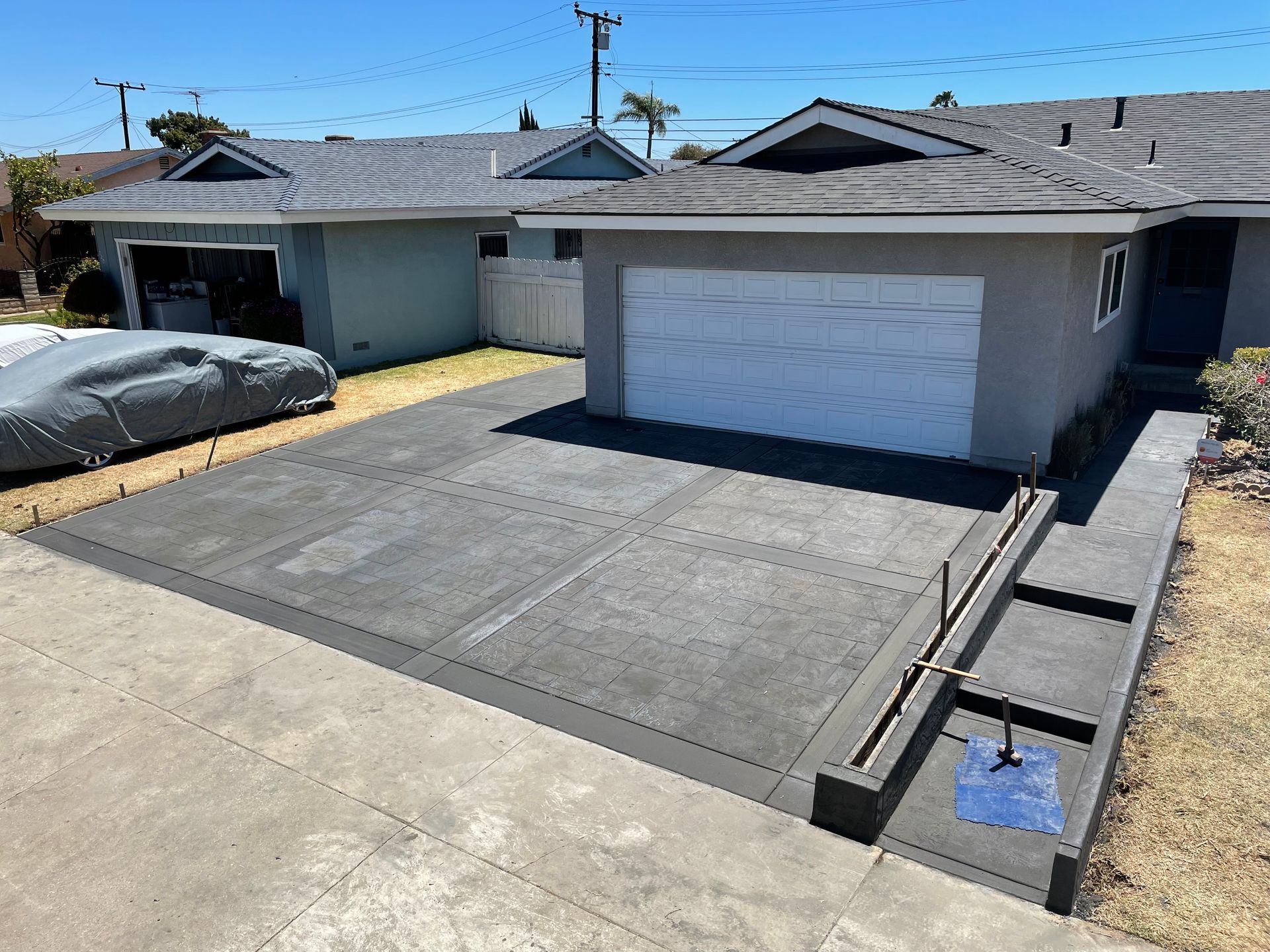 Residential driveway with a white garage door and concrete ramp beside a curb channel