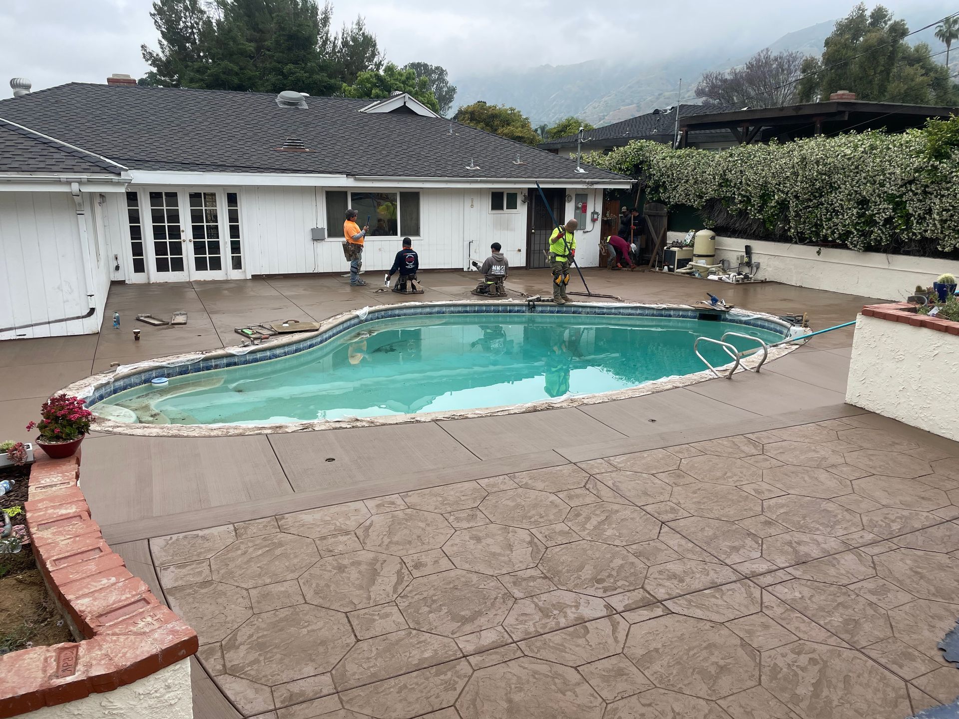 Quarry stone stamp slab and broom finish slab around pool in Chino California