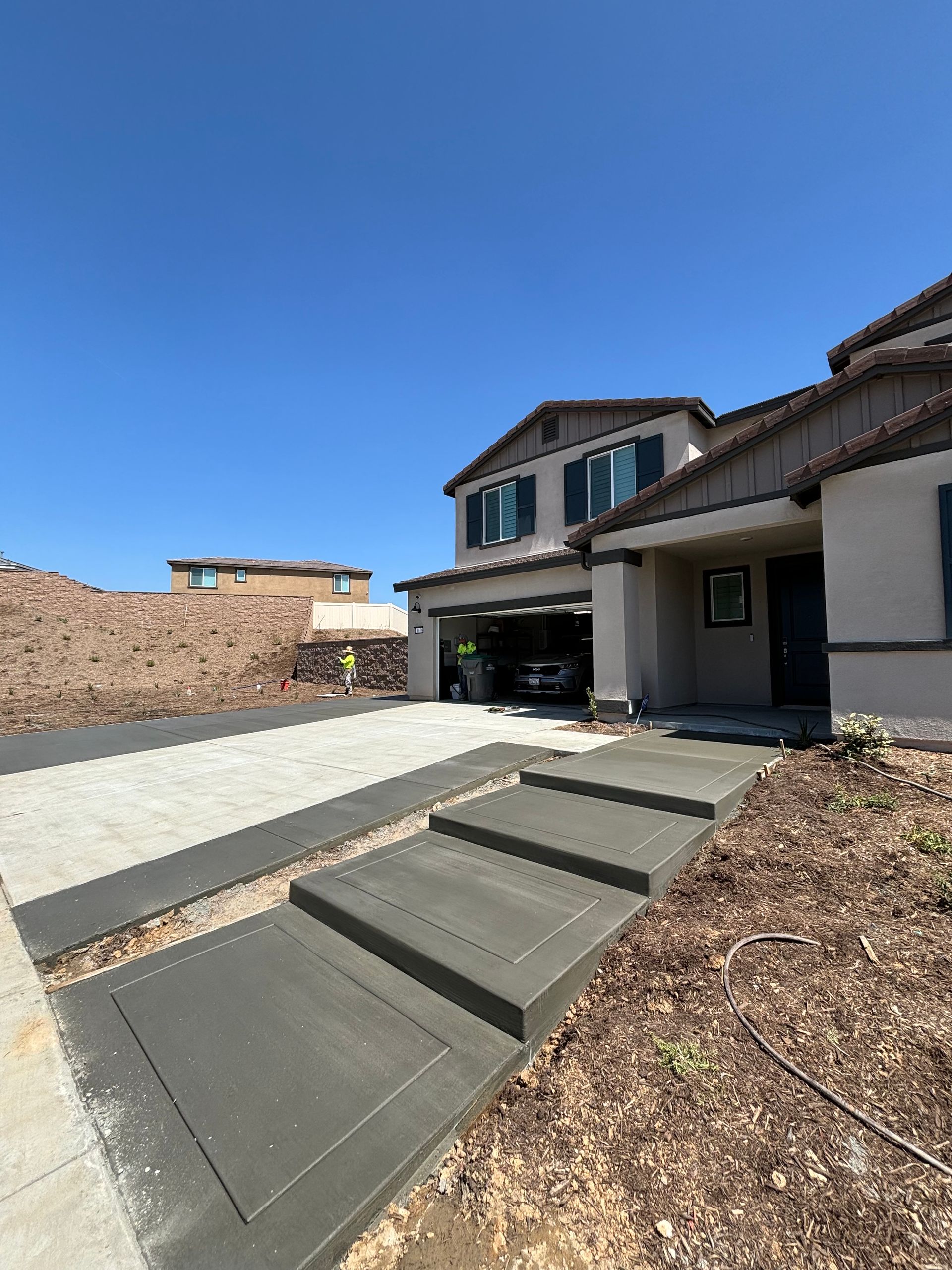 Modern suburban house with a driveway, front steps, and a garage under a clear blue sky