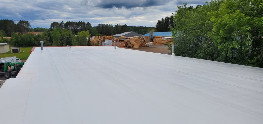A large white roof with a lot of trees in the background.