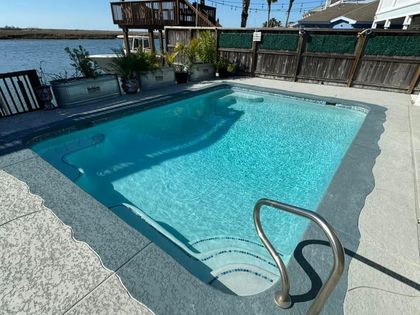 Swimming pool with steps and a handrail. Outdoor setting with a river in the background.