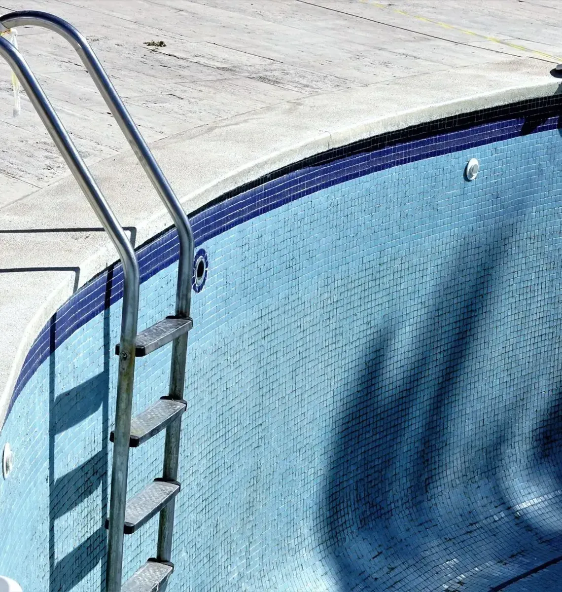 Blue swimming pool with ladder and shallow water at the edge
