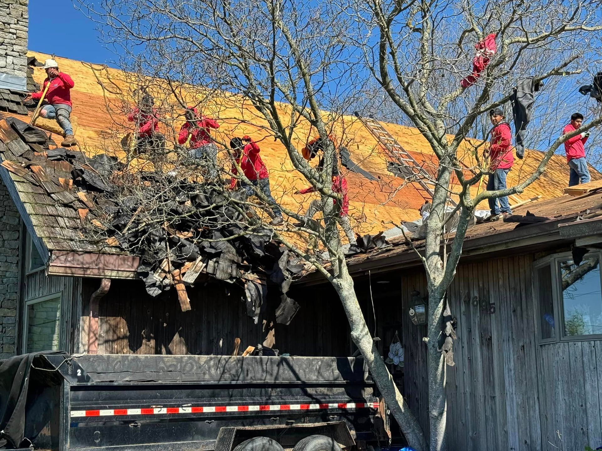 A group of men are working on the roof of a house.