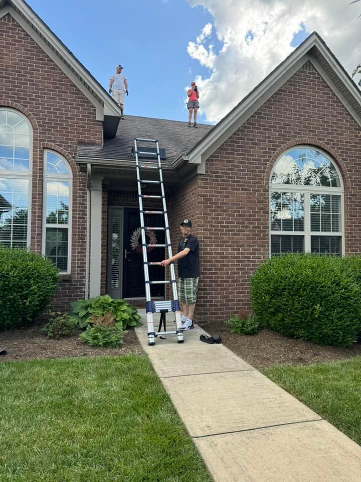 A man with a ladder is standing in front of a brick house.