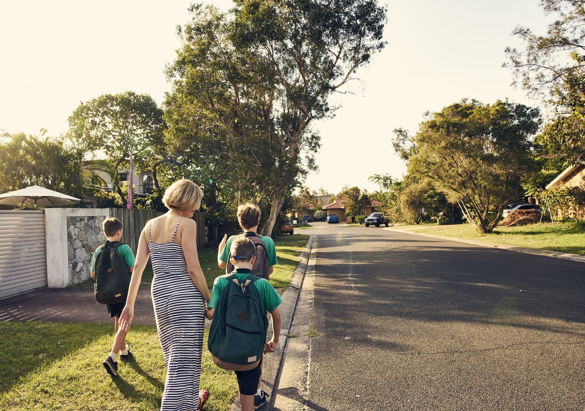 A family is walking down a dirt road with cows in the background.