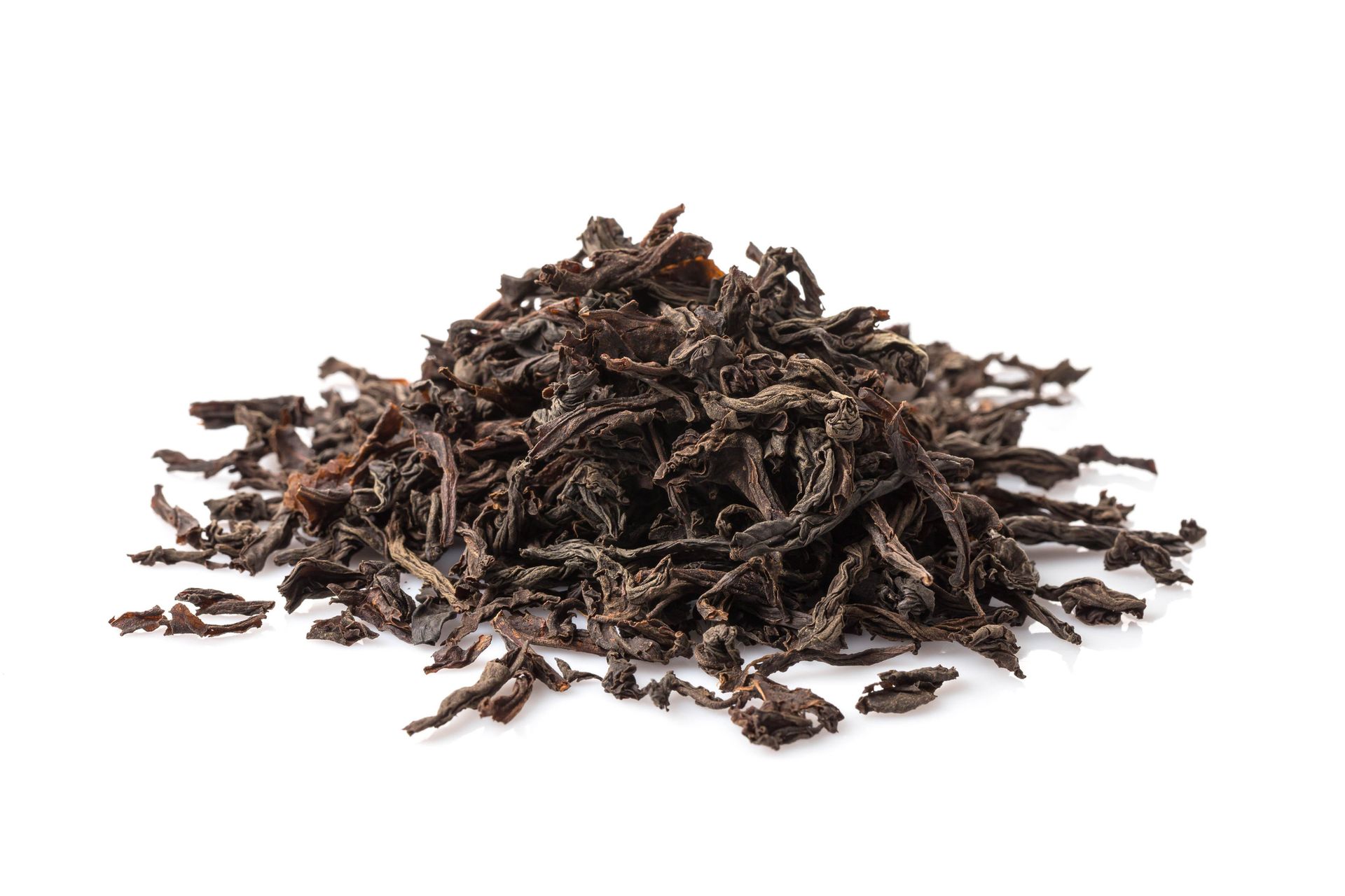 Pile of dark brown, loose-leaf tea on a white background.