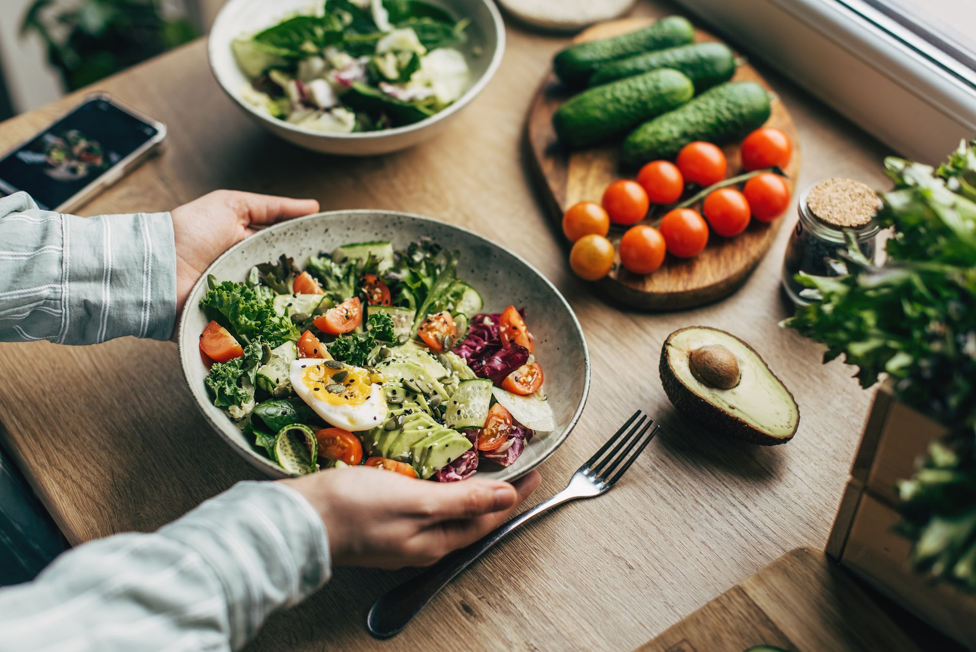 A pair of hands holds a salad full of superfoods and healthy ingredients.