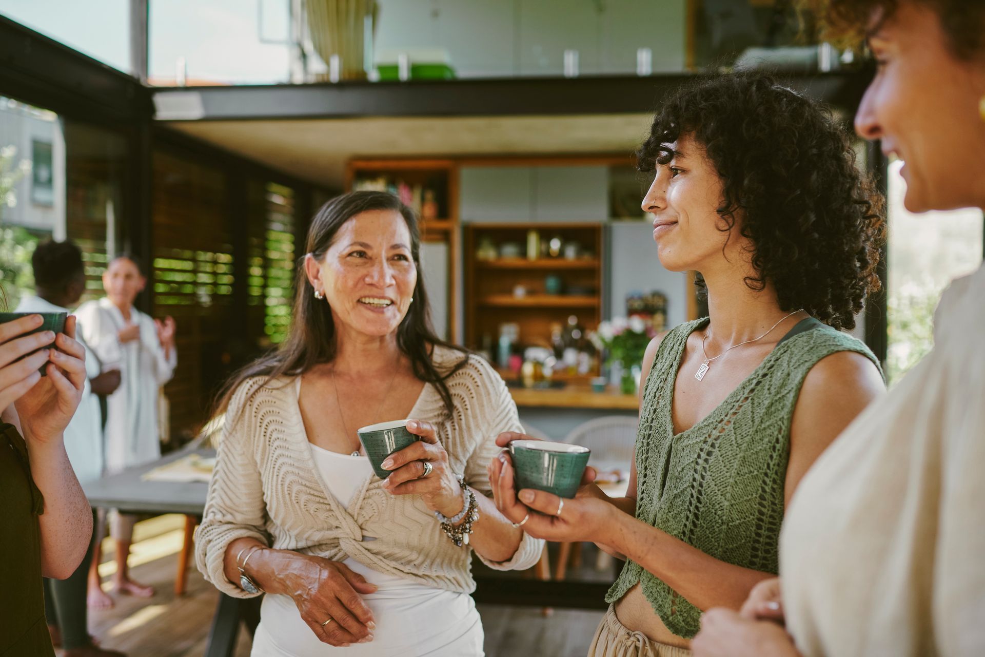 Diverse group of smiling female friends talking and drinking cups of herbal hot tea in a tea house. Diverse group of smiling female friends talking and drinking cups of herbal hot tea in a tea house.