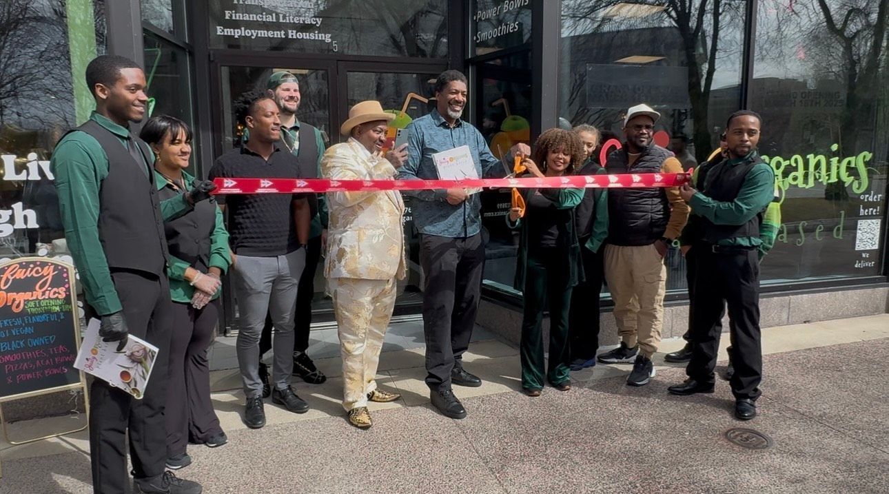 People cutting a red ribbon at the entrance of a business, likely a grand opening.