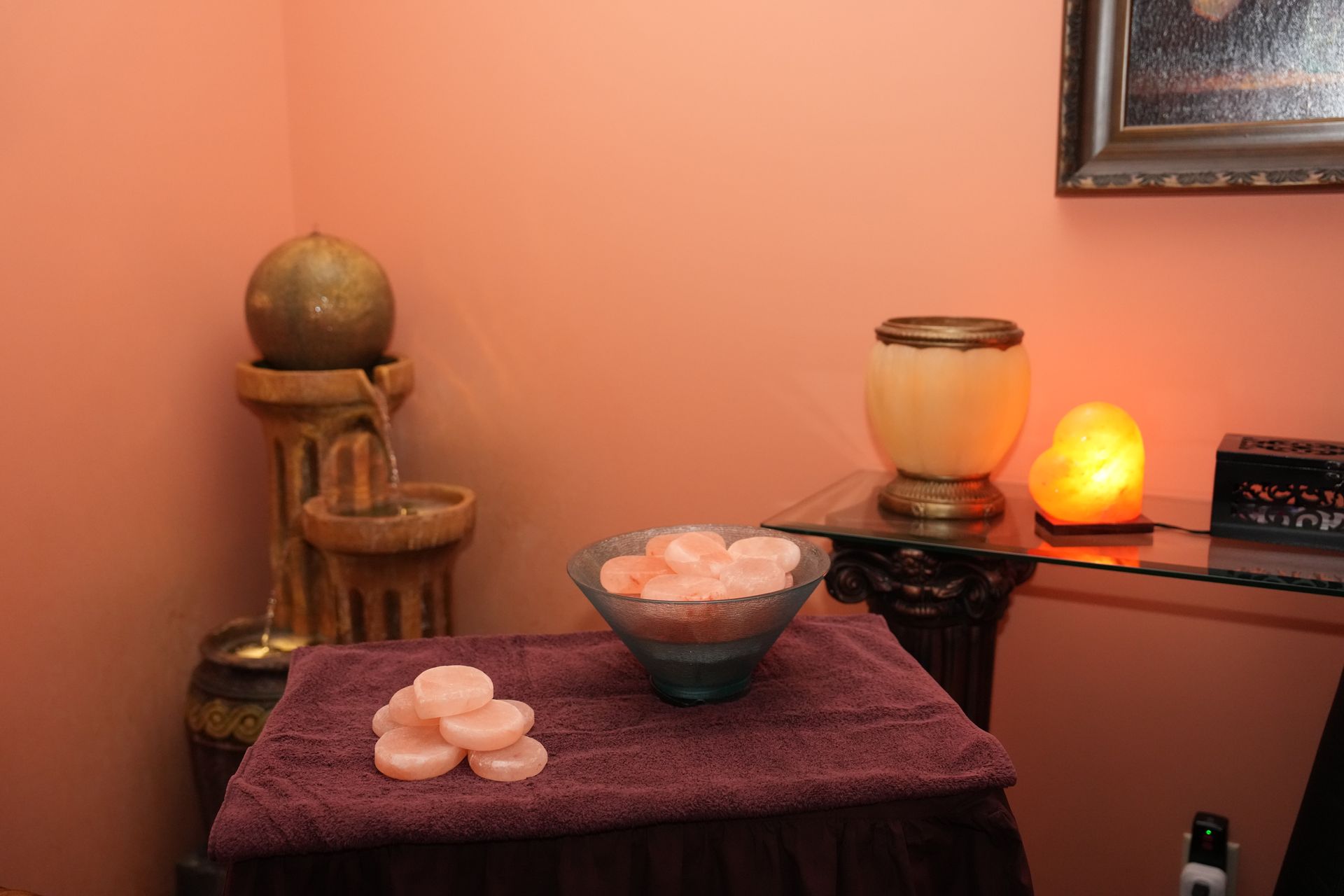 Spa table with rose petals, candles, and warm amber lighting against a peach wall