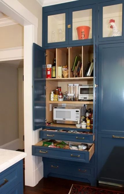 A kitchen with blue cabinets and drawers and a microwave.