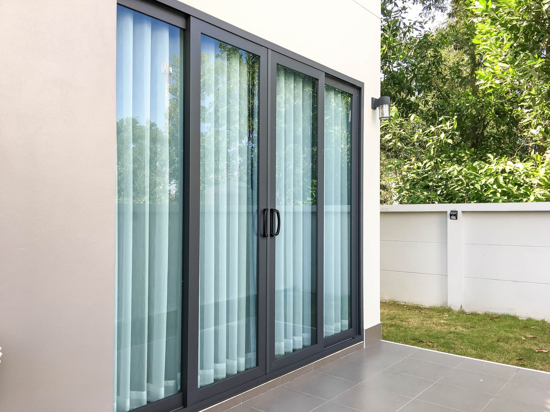 A house with sliding glass doors and curtains on the windows.