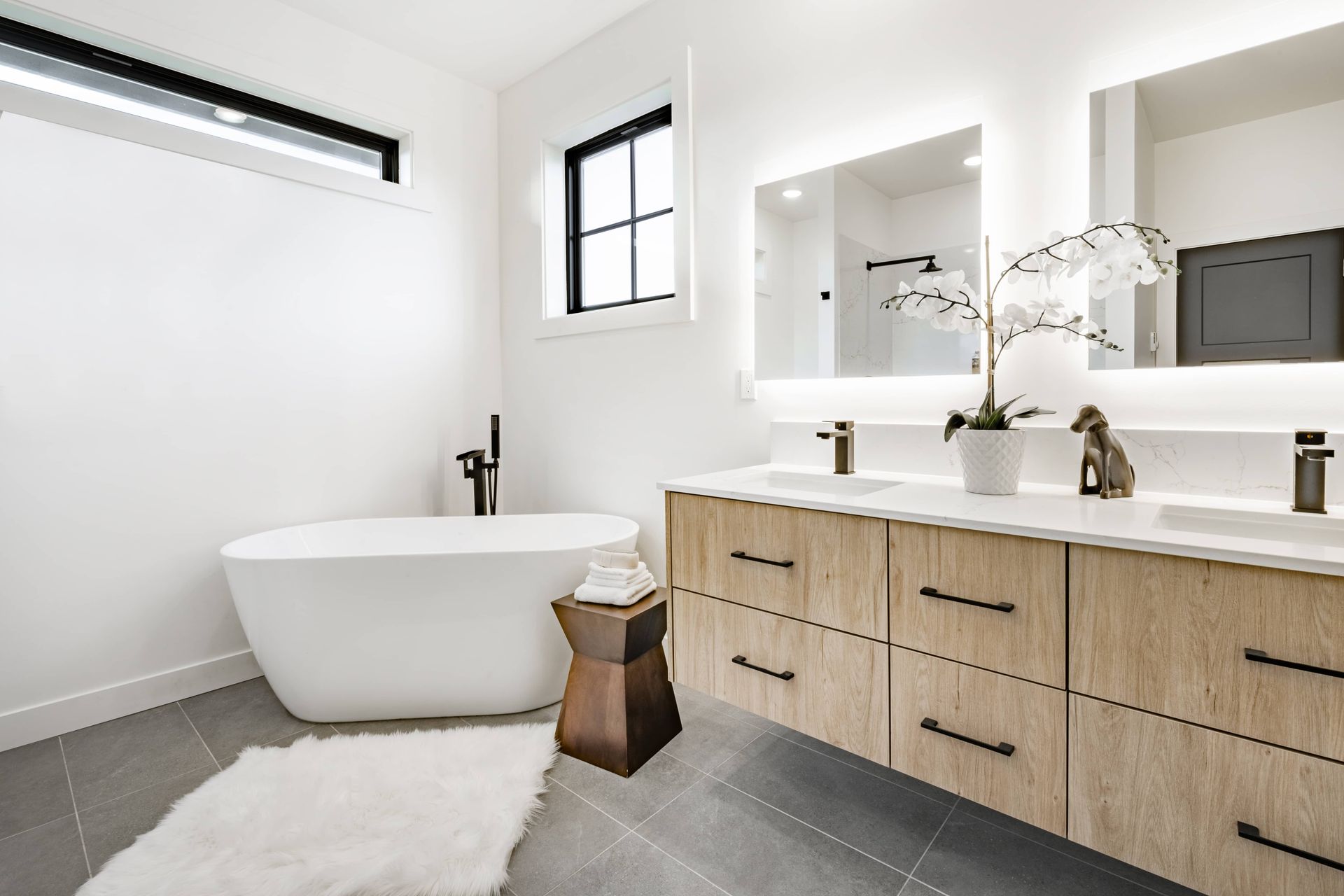 A bathroom with a bathtub, sinks, mirrors, and a window.