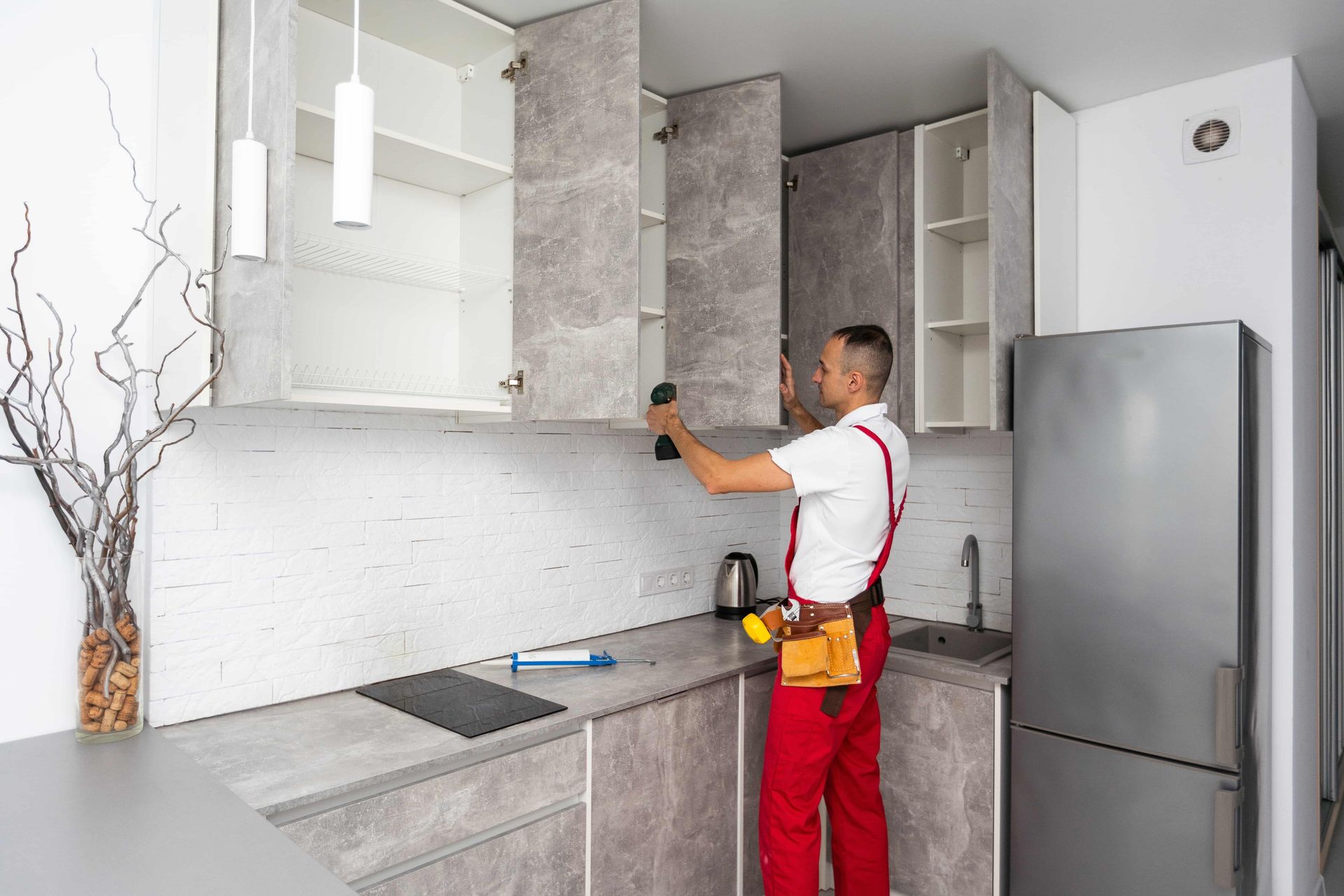 A man is installing cabinets in a kitchen.