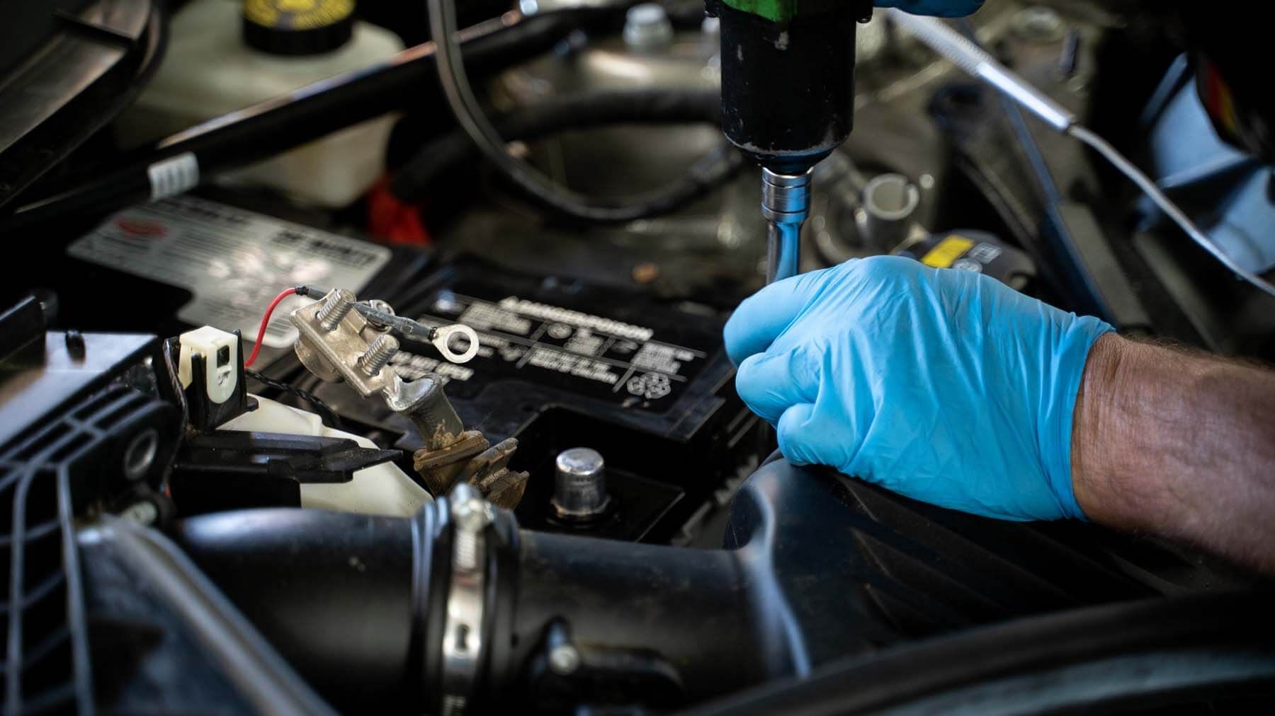 A person is working on a car battery with a drill. | The Euro Shop