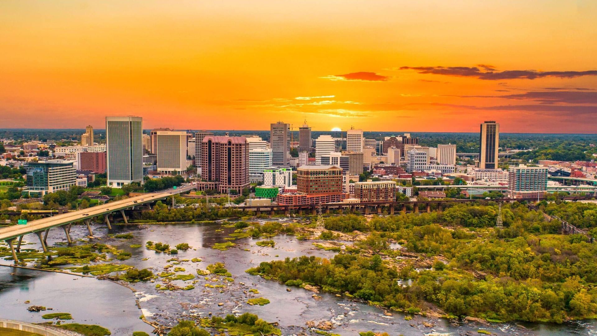 An aerial view of a city skyline at sunset with a river in the foreground. | The Euro Shop