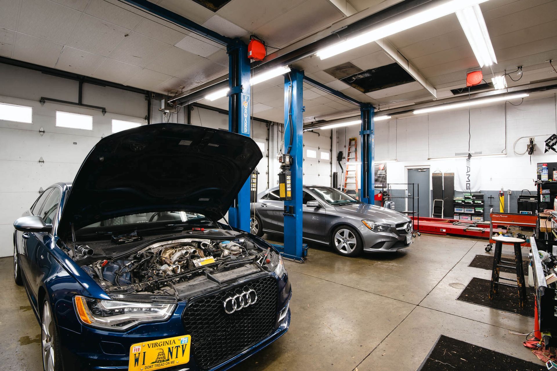 A blue audi is parked in a garage with its hood up. | The Euro Shop