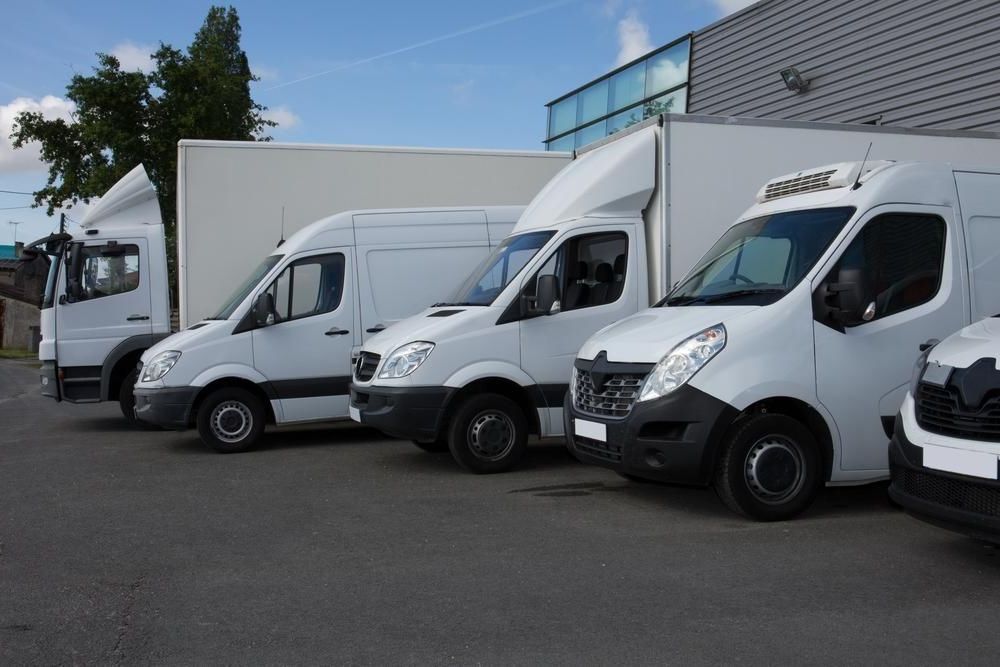 A Row Of White Vans Parked Next To Each Other In A Parking Lot — R2B Heavy Vehicle Driving School In Mackay, QLD