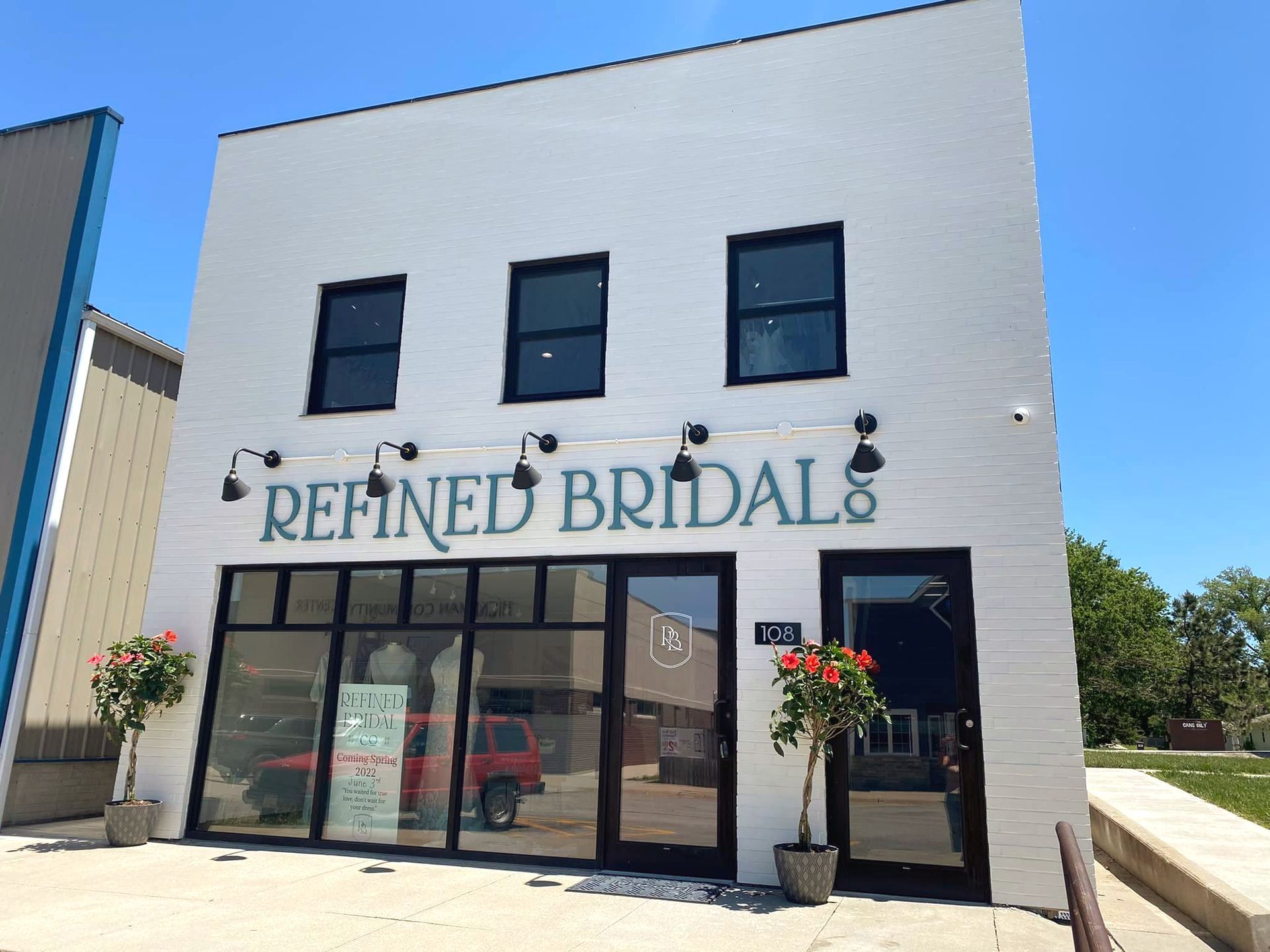 A white building with a green sign that says refined bridals