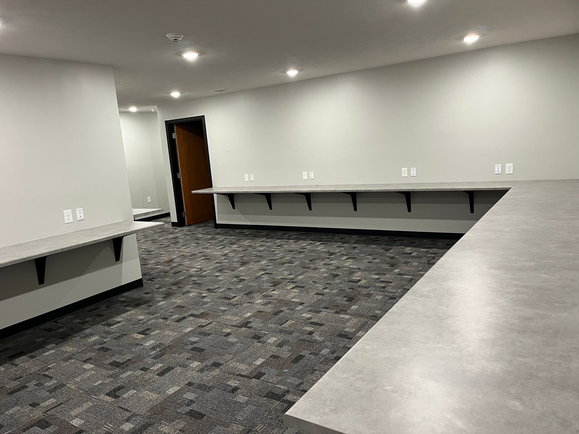 A large empty room with a carpeted floor and a long counter.