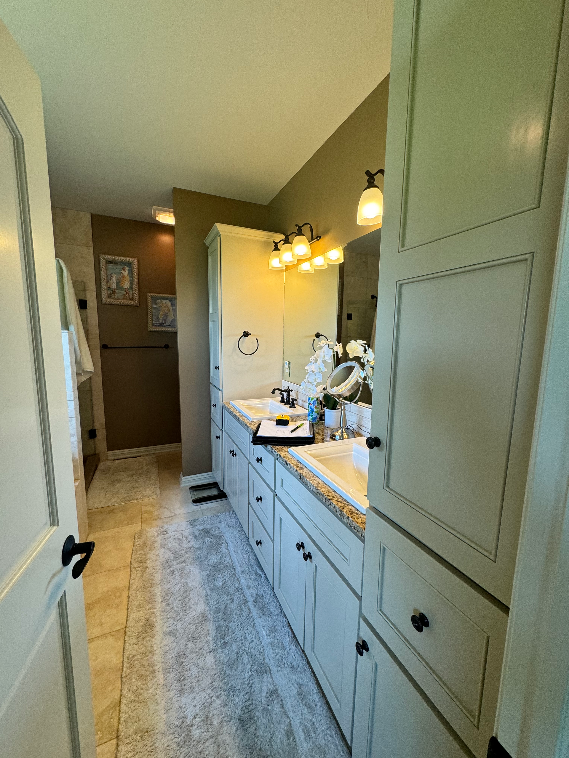 Bathroom with white cabinets, dual sinks, mirror, and tan walls.