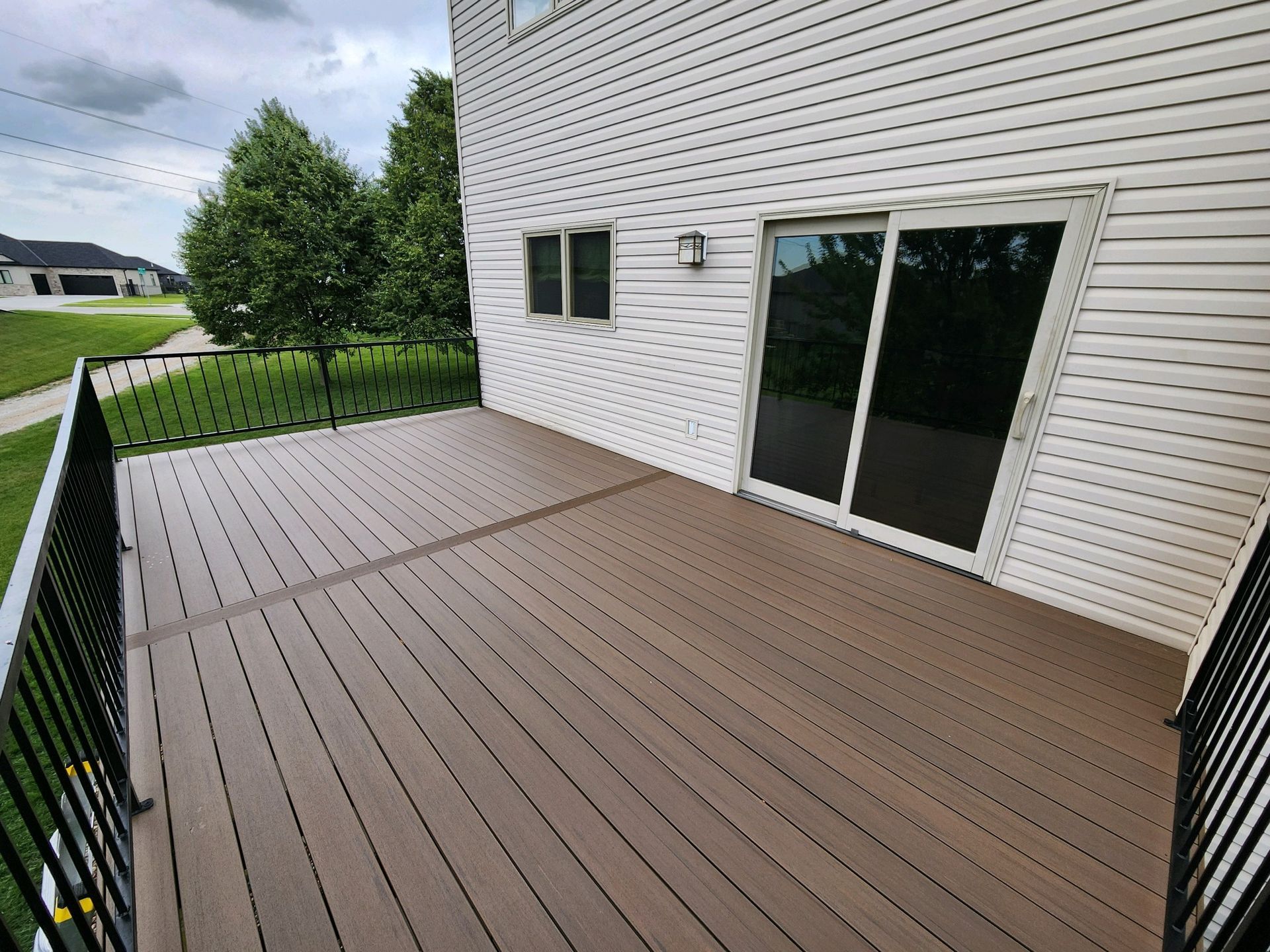 A large deck with a sliding glass door in the backyard of a house.