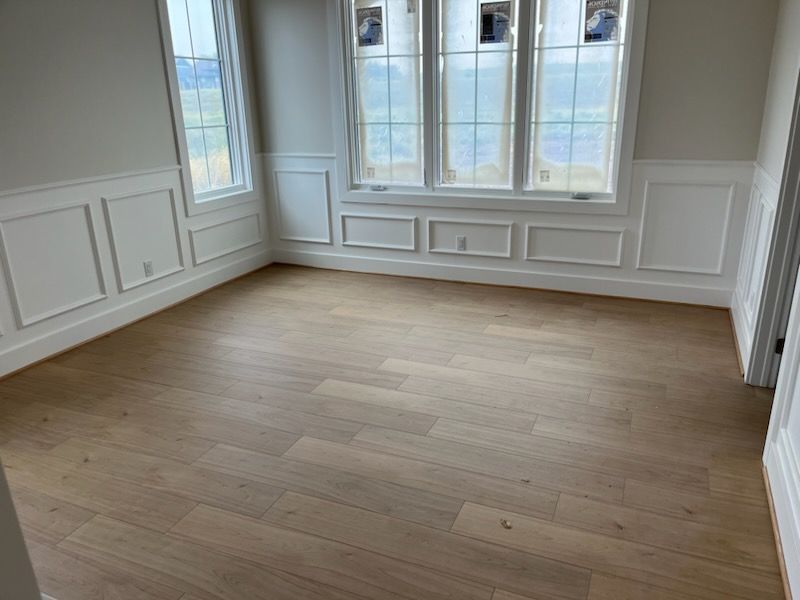 An empty room with hardwood floors and white trim.