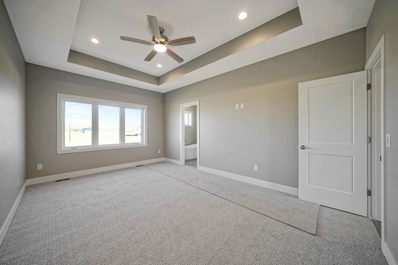 An empty bedroom with a ceiling fan and a lot of windows.