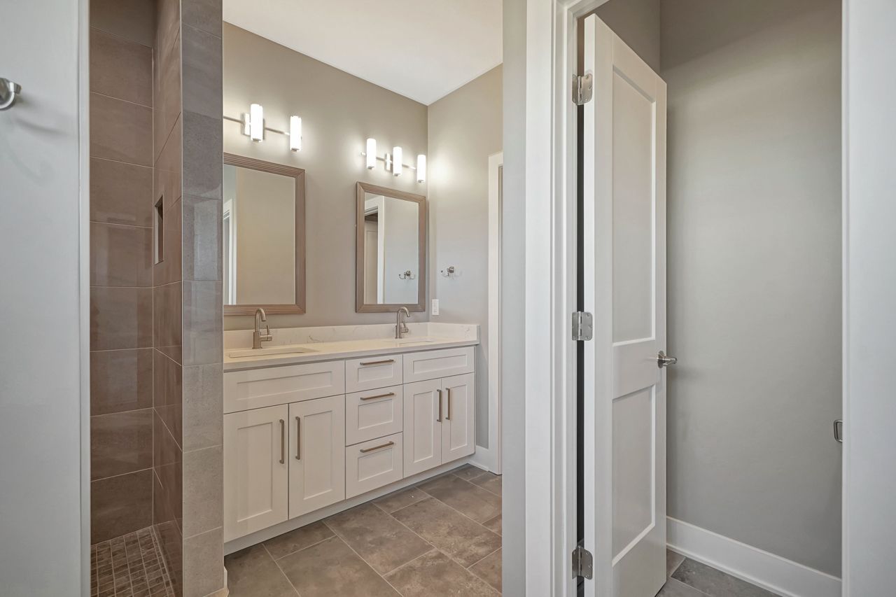 A bathroom with two sinks and a walk in shower.