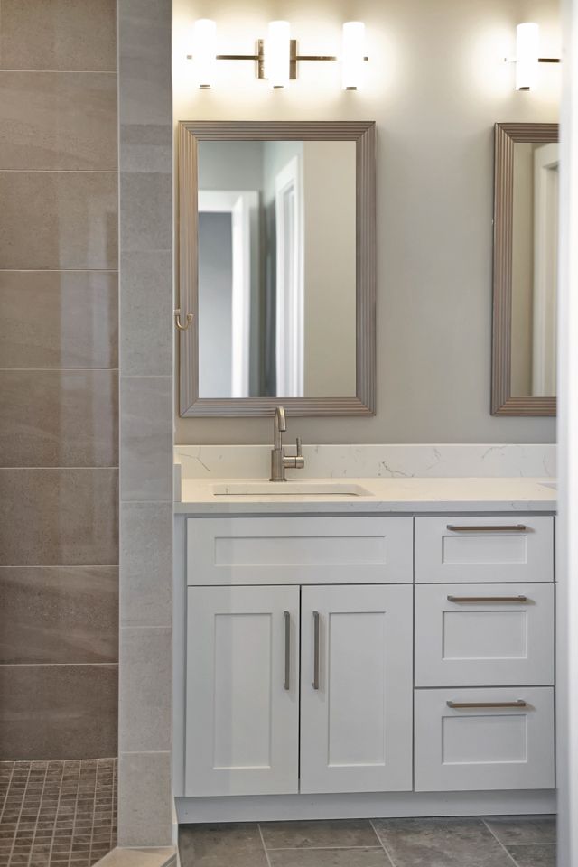 A bathroom with a sink , mirror and shower.