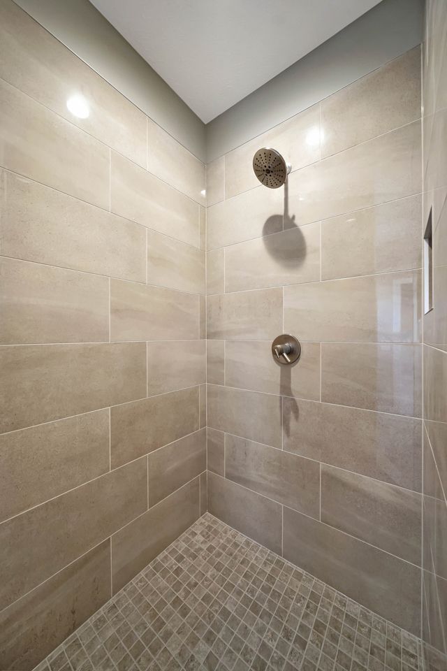 A walk in shower with tiled walls and a tiled floor.